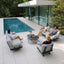 People relaxing on modern outdoor furniture by a poolside.